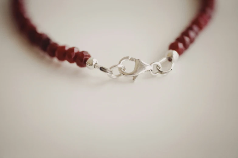 a silver knot on a red beaded necklace