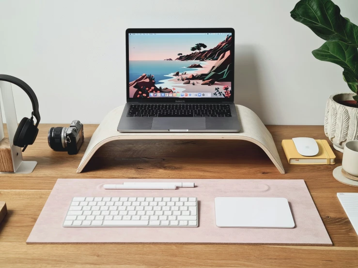 a desk with a laptop, keyboard and headphones