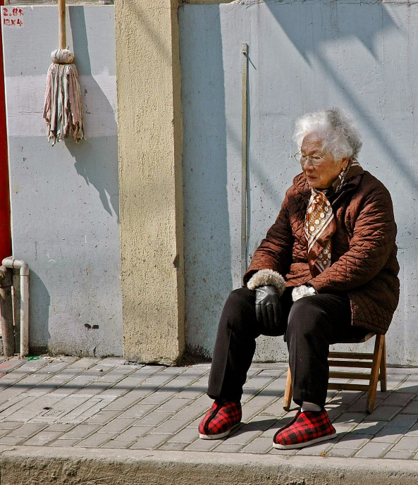 an old man sits in a chair as he looks down at his feet