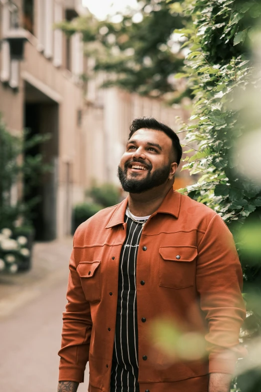 a man in a red shirt looking up with trees in the background