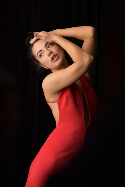 a woman in a red dress posing in front of a black background