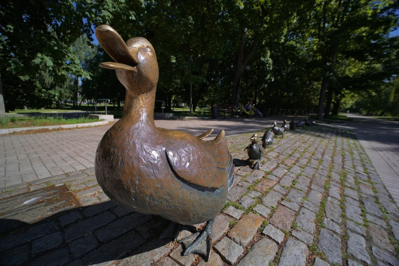 several bronze ducks sitting on brick ground near tree lined area