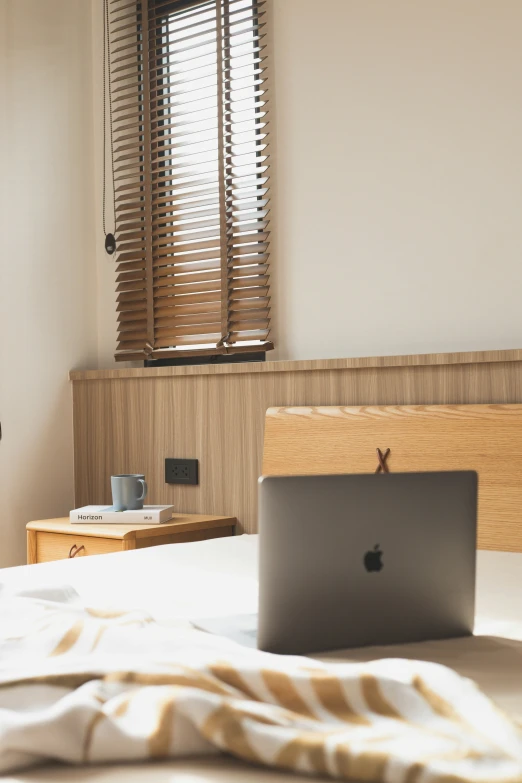 a white bed topped with a laptop computer sitting on top of a table