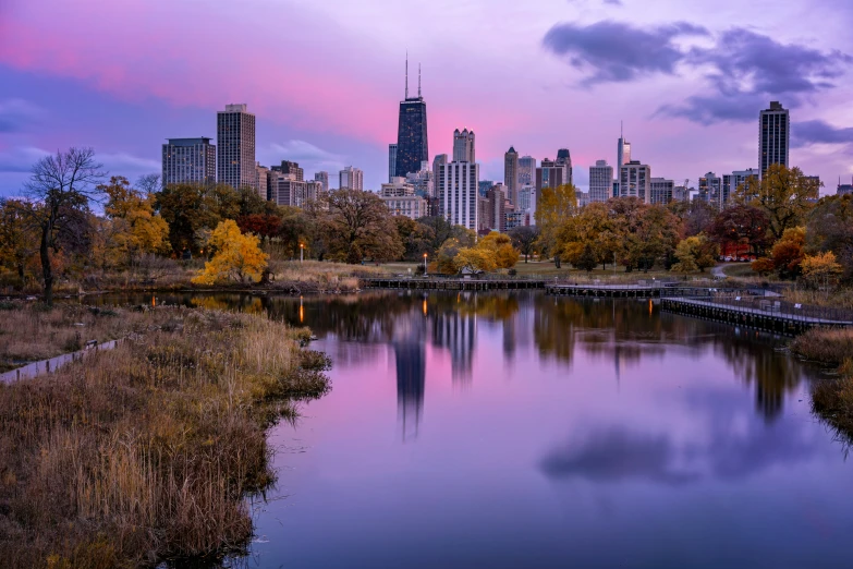 a river with buildings in the distance with clouds