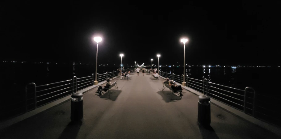 many people on a walk way with some street lights