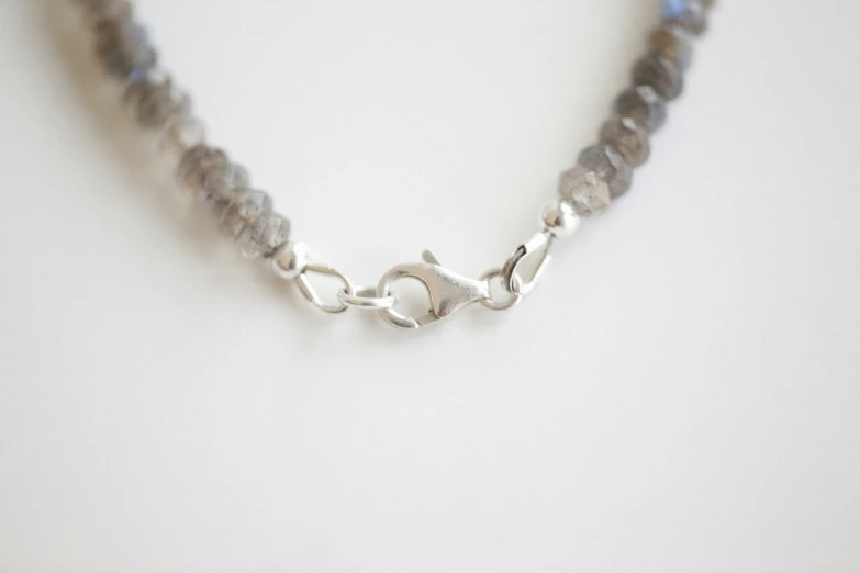 a white background with a single silver bead necklace