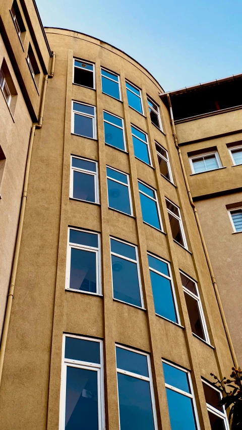 a tall brown building with windows and trees near it