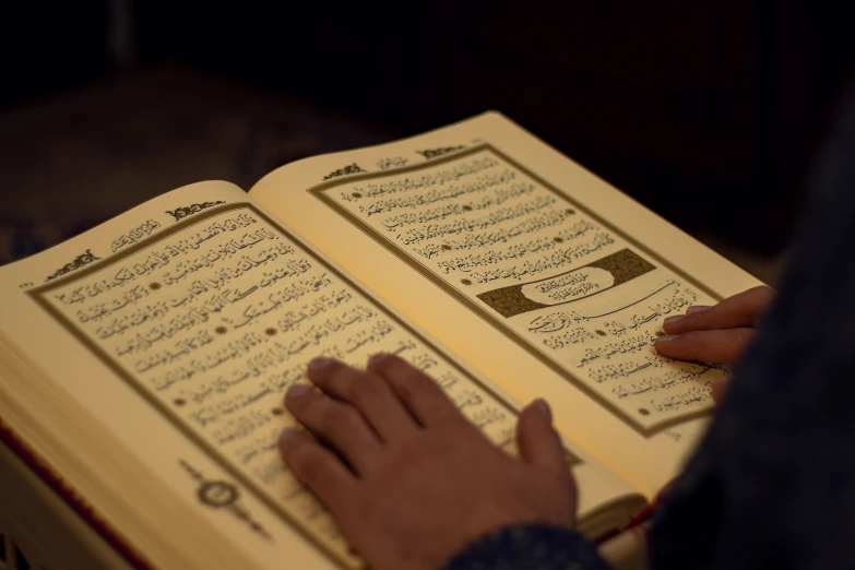 a person that is holding an islamic book