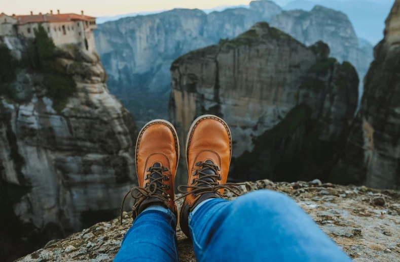 someones feet are propped up on top of a cliff