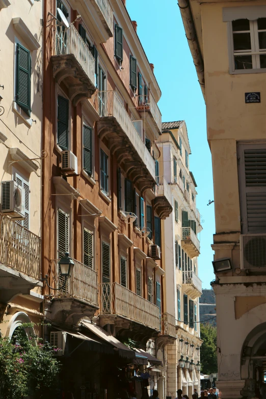 a city street with old, brown buildings and people walking by