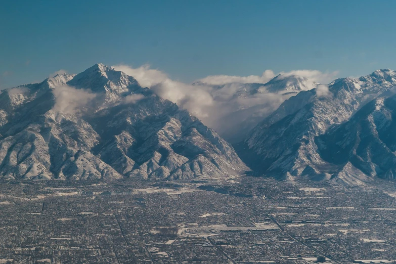 mountains covered with snow near a city under a cloud filled sky