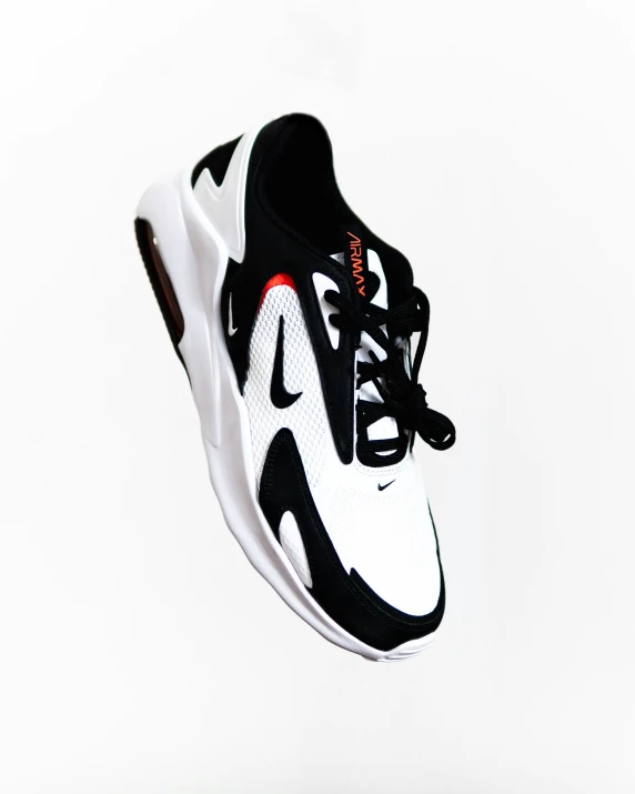 a black and white sneaker shoe that has a red line on it