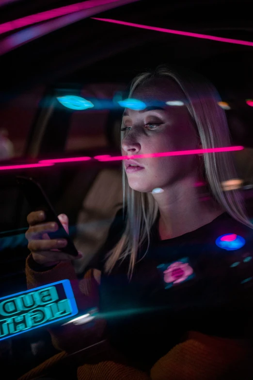 a woman driving a car on a street with neon lights