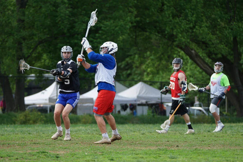 three boys are playing lacrosse in the field