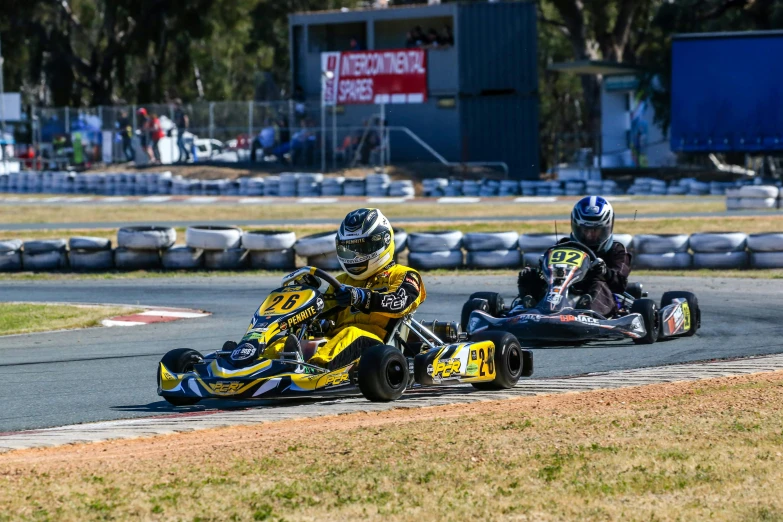 two people on a small motorcycle with an adult racing in the background