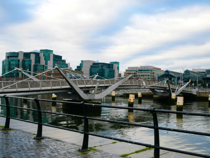 some buildings are along the water and the bridge is very long