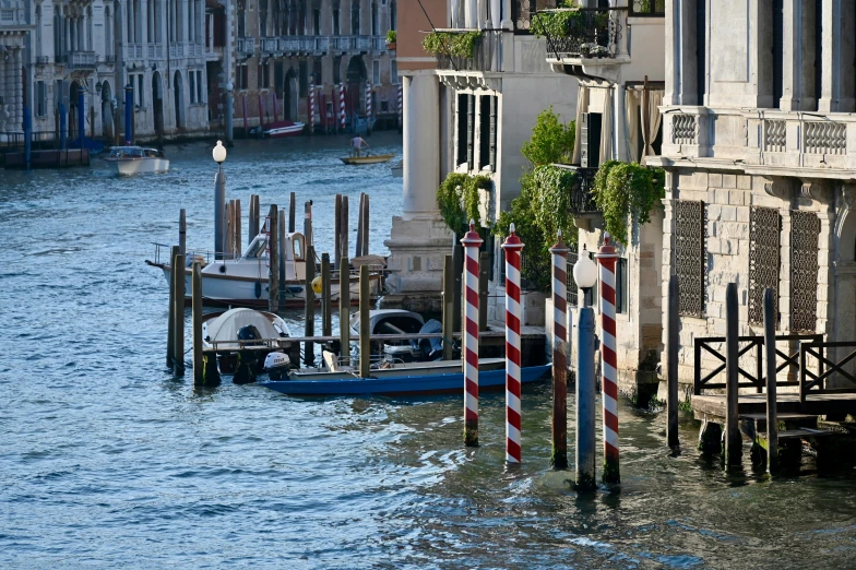 many boats are tied up to posts on the side of a road