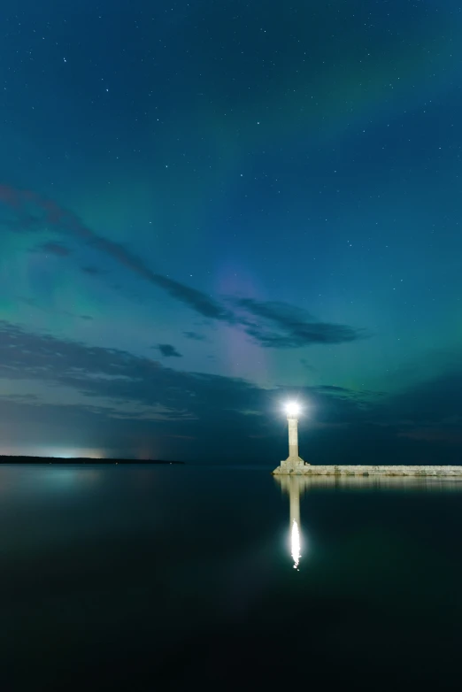 a light tower in the water with a night sky background