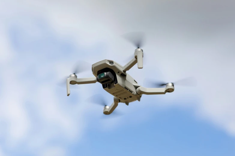 a camera attached to a large gray and yellow quad - rotored vehicle flying in the air