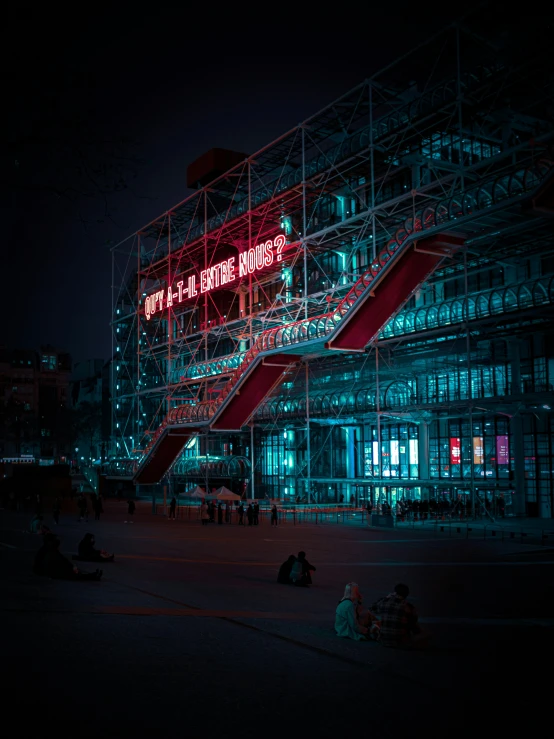 several people sit and stand outside a building at night