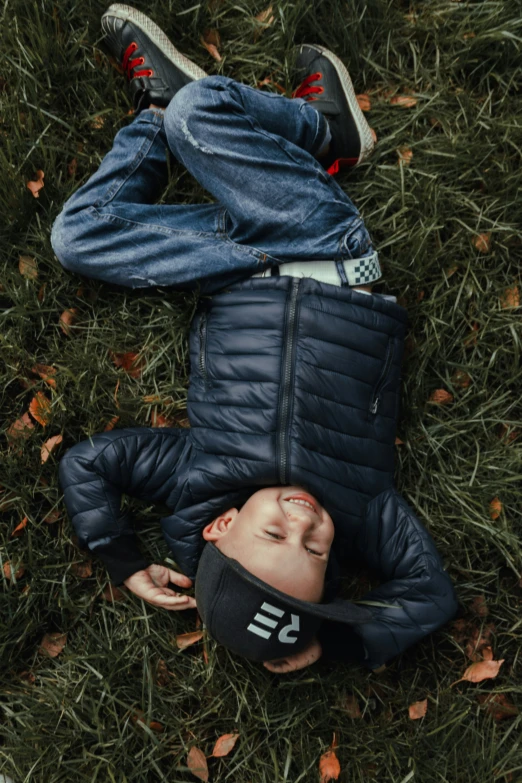 an overhead view of a young man laying on the grass in his leather jacket