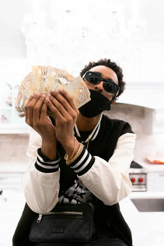 a man wearing sunglasses and a black mask while holding up a fan of money