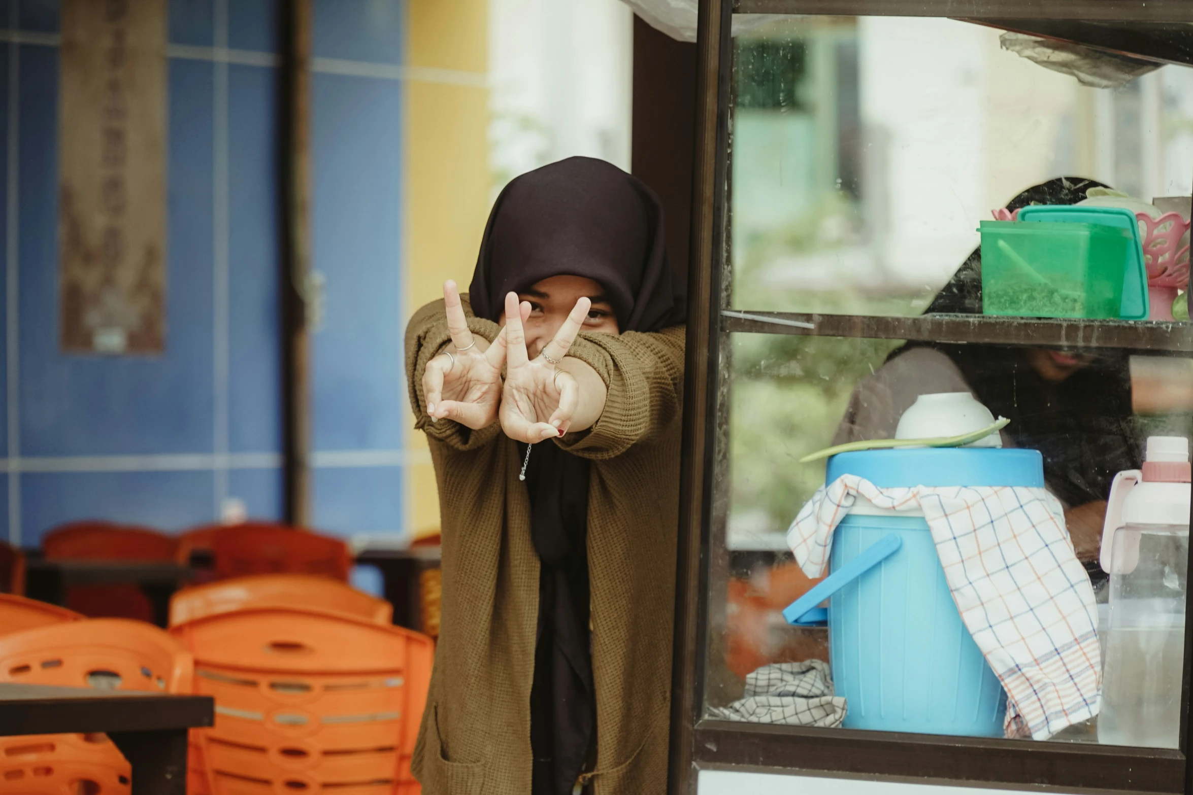 a woman standing in front of a store and holding up doughnuts