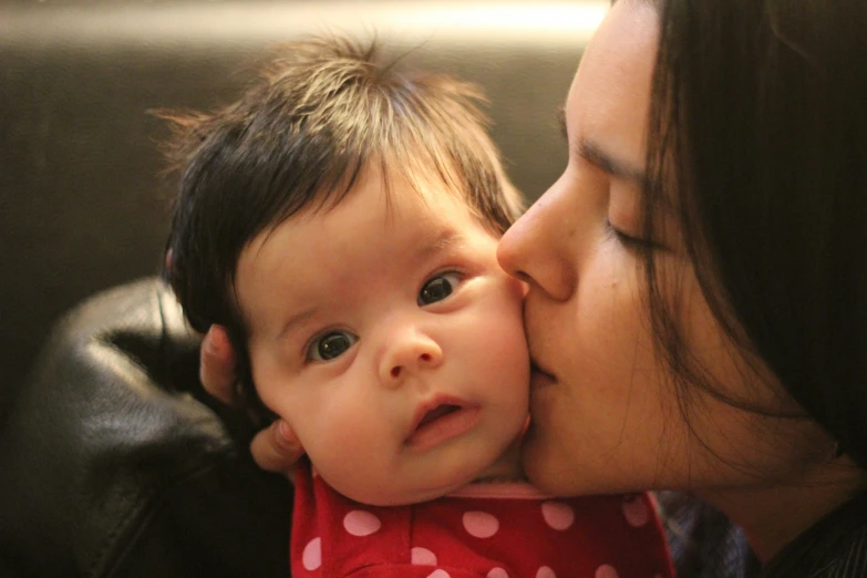 woman in red shirt kissing child on cheek