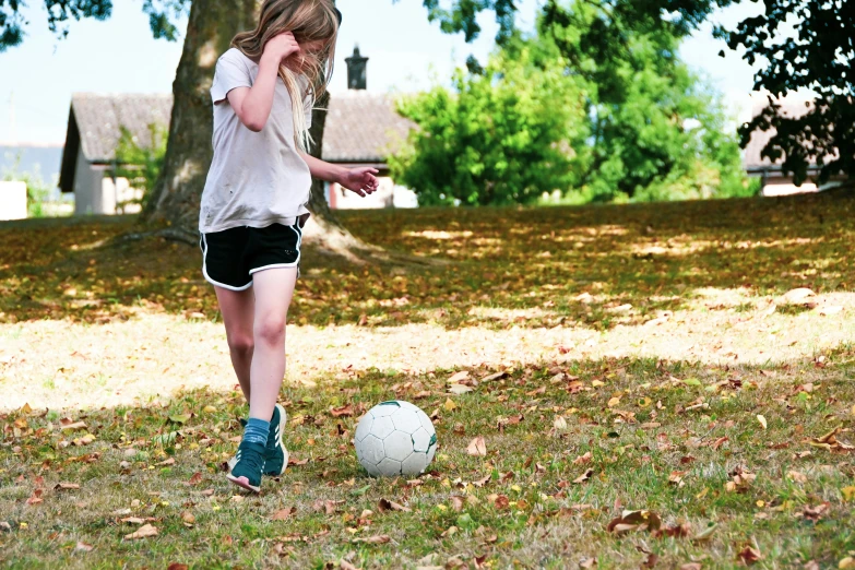 a little girl stands and plays with a ball