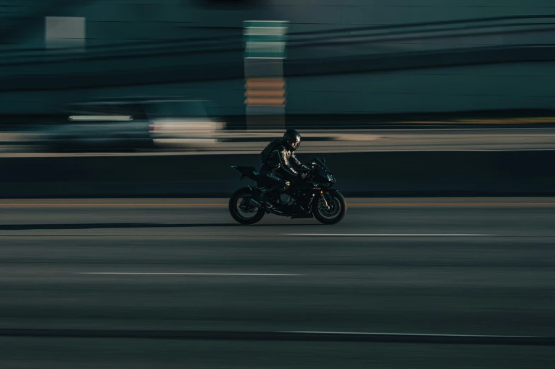 a motorcycle rider speeds down the street past a car
