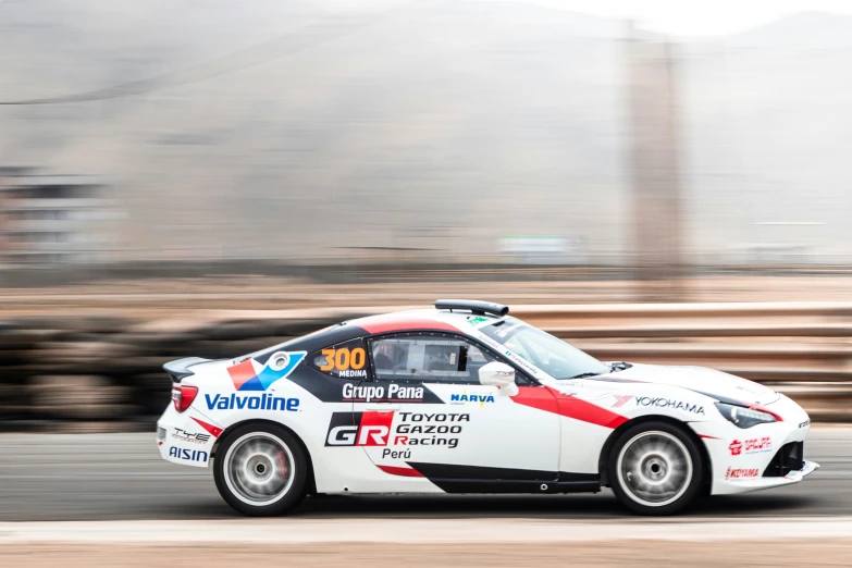 a racing car driving on a road with mountains in the background