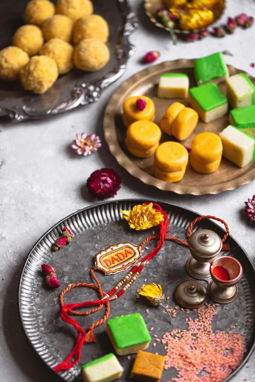 two trays with colorful sweets in them next to plates of small food