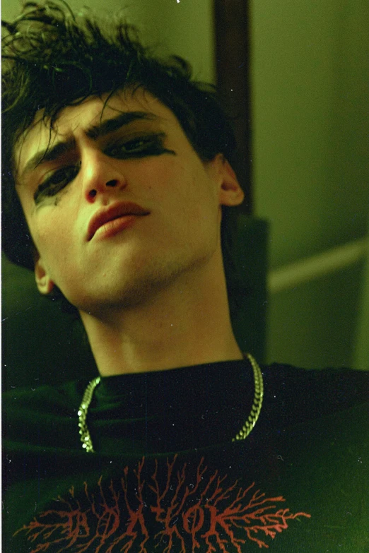 a boy with dark colored makeup and long necklace