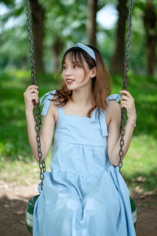 a girl sitting on a swing in the park