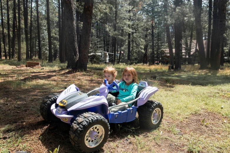 two s sitting on a small blue toy atv