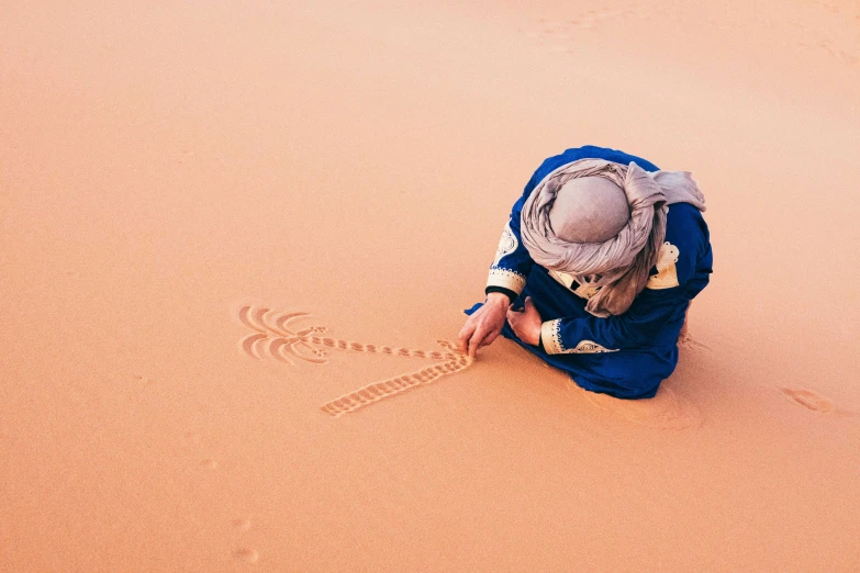 a person who is kneeling down in the sand