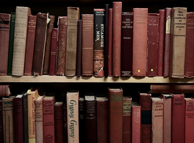 an old book shelf with many red and yellow books on it