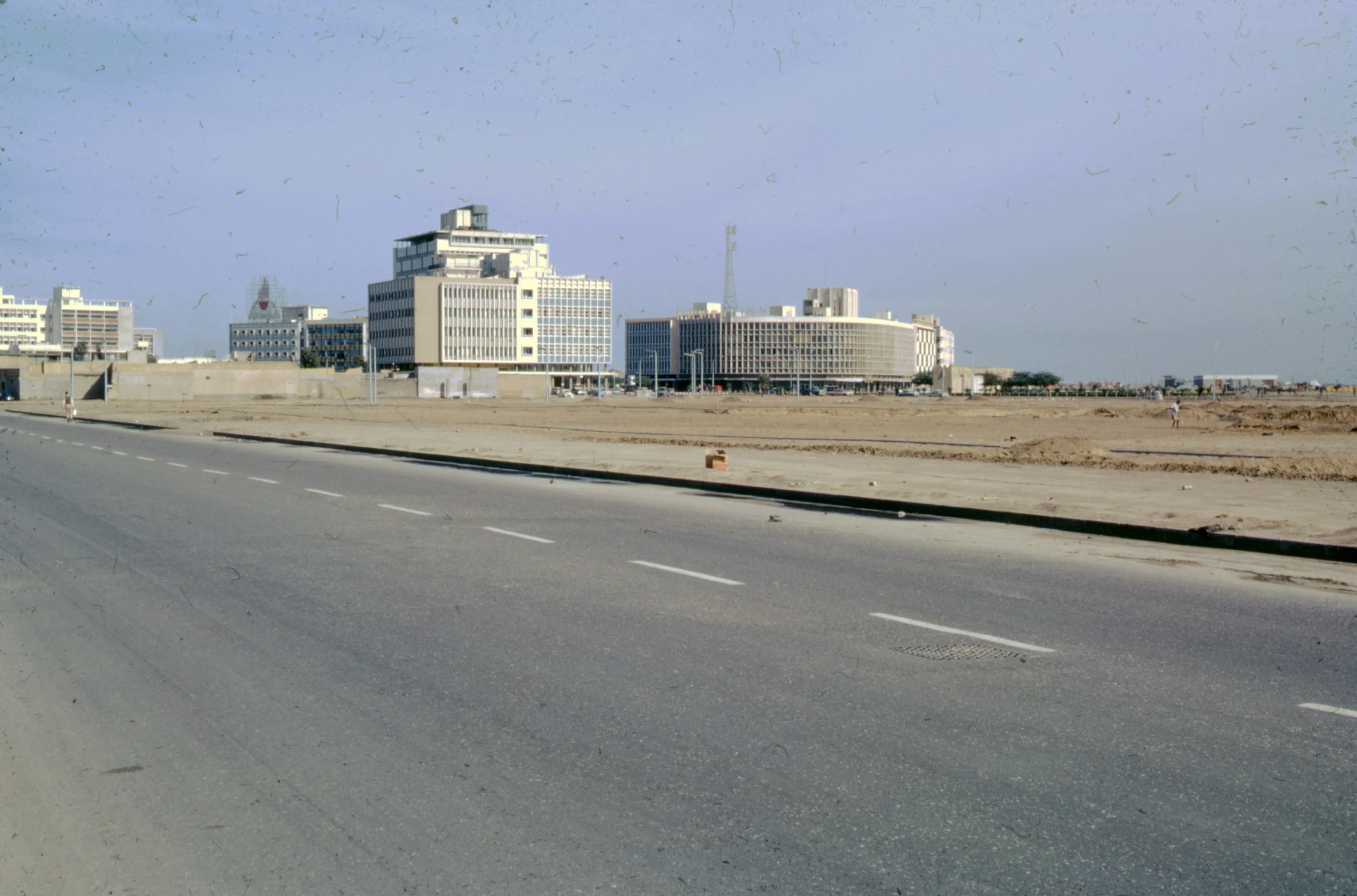 the road leading to the city with a red fire hydrant on one side and buildings in the distance