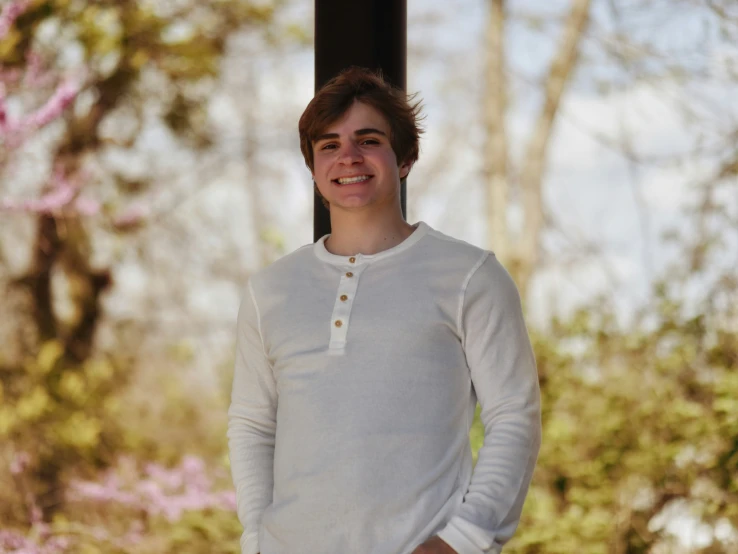 a boy is smiling while standing under some trees