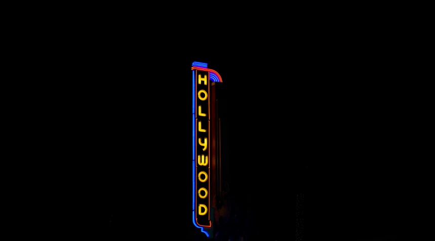 a sign lit up at night in front of dark sky