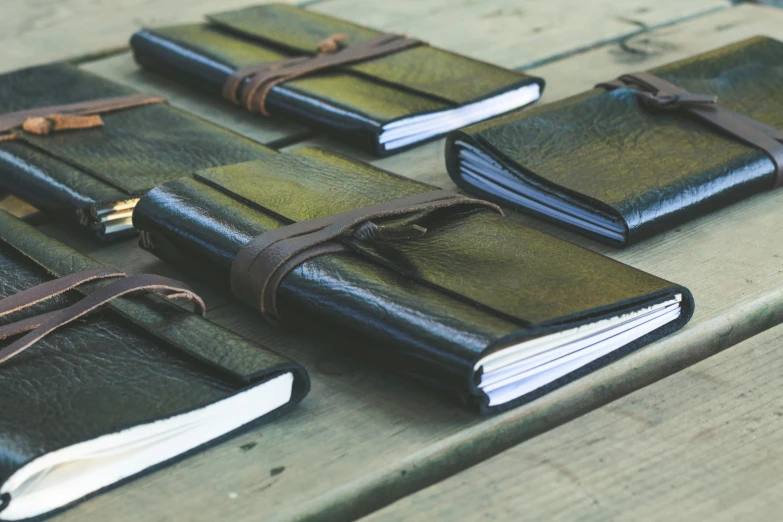 six small green leather notebooks laying on a table