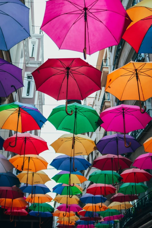 lots of umbrellas suspended in the air outside an office building