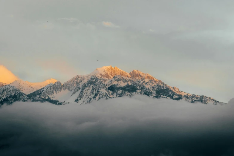 a mountain covered in lots of snow under a cloud filled sky