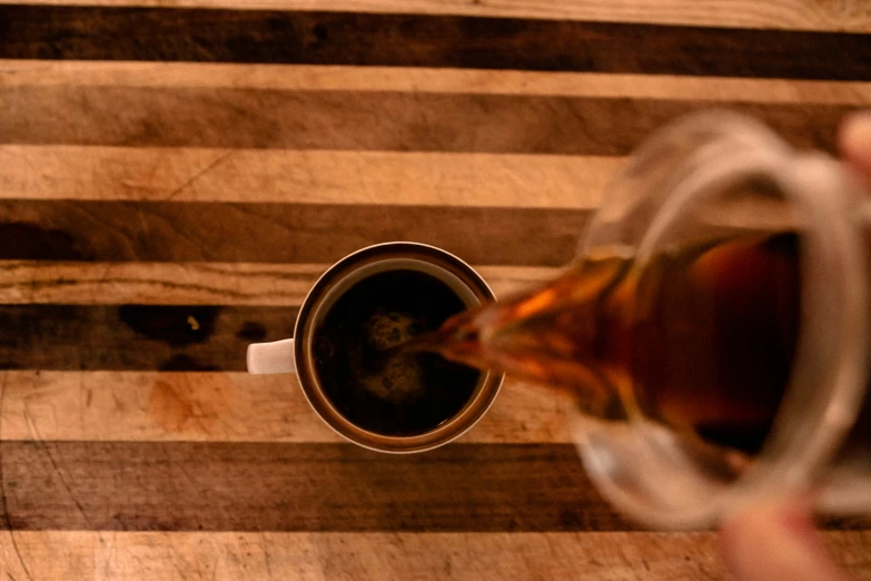 tea being poured into a cup on a wooden  board