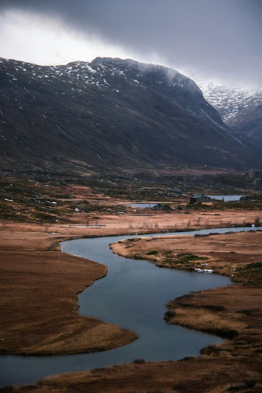 a river in an alpine region surrounded by snow covered mountains