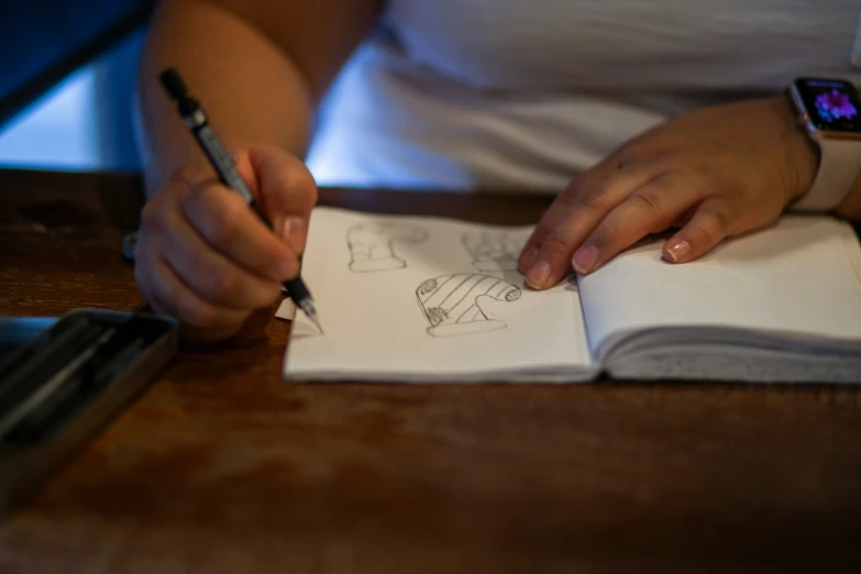 a person is drawing on some paper with a pen