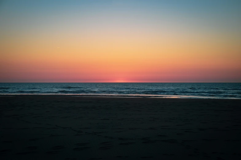 the sun setting over the ocean with the water slightly choppy