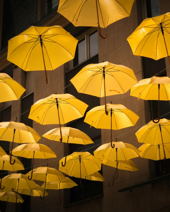 the rows of yellow umbrellas are hanging above the building