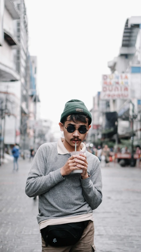 a man in sunglasses and a hat drinking coffee