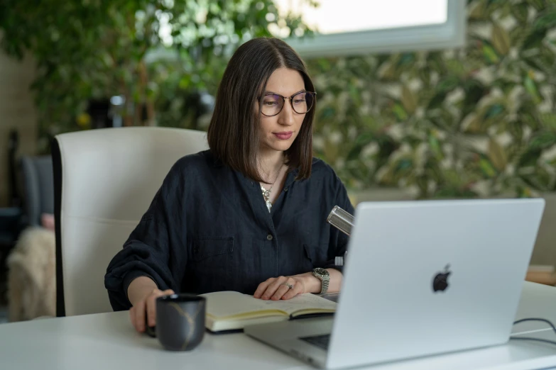 a woman is working on her laptop at a desk